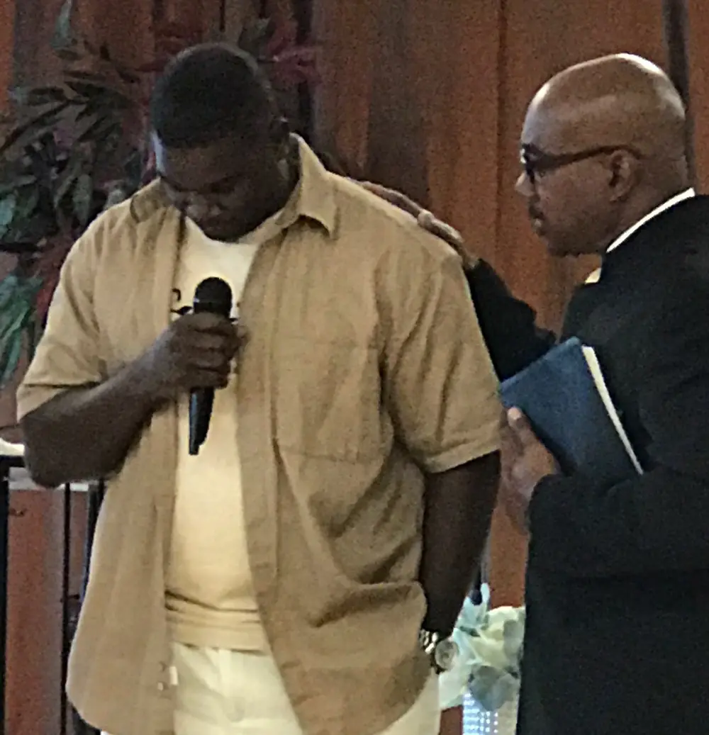 Pastor Herkie praying with a member of the congregation